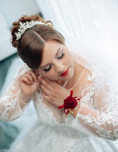 Braut beim Anlegen ihrer Ohrringe am Hochzeitstag – elegant, ausdrucksstark und liebevoll gestylt. Hochzeitsfotografie Lahr mit Persönlichkeit.