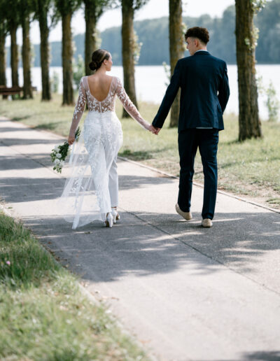 Braut und Bräutigam spazieren Hand in Hand am Wasser entlang – Hochzeitsfotografie Lahr mit Persönlichkeit.