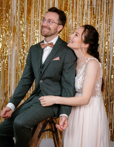 Glückliches Brautpaar vor goldener Glitzerwand – moderne Hochzeitsfotografie Lahr mit Persönlichkeit.