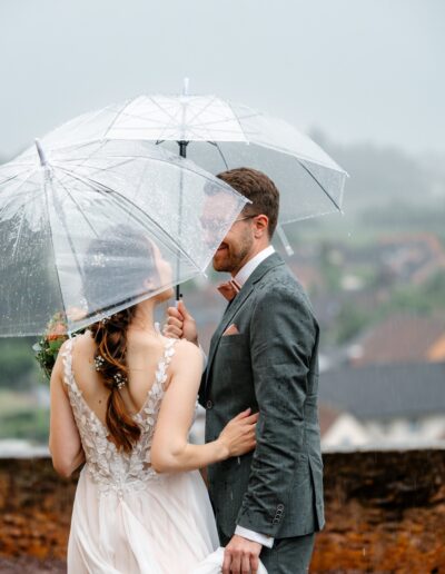 Das Paar genießt einen stillen Moment über den Dächern bei Regen – eine intime Szene voller Gefühl in bester Hochzeitsfotografie Lahr mit Persönlichkeit.