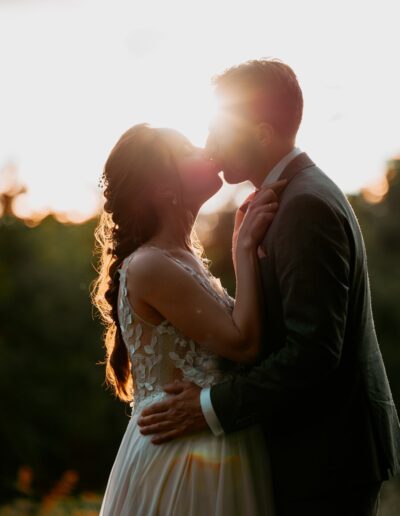 Hochzeitskuss im Abendlicht: Das Brautpaar küsst sich innig im goldenen Licht der untergehenden Sonne – ein sinnlicher Moment voller Intimität.