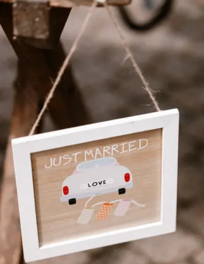 Ein kleines Holzschild hängt an einem Nagel mit "just married"