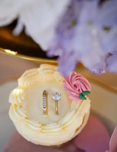 Eine Nahaufnahme eines cupcakes, in ihm stecken zwei Ringe in der Buttercreme.